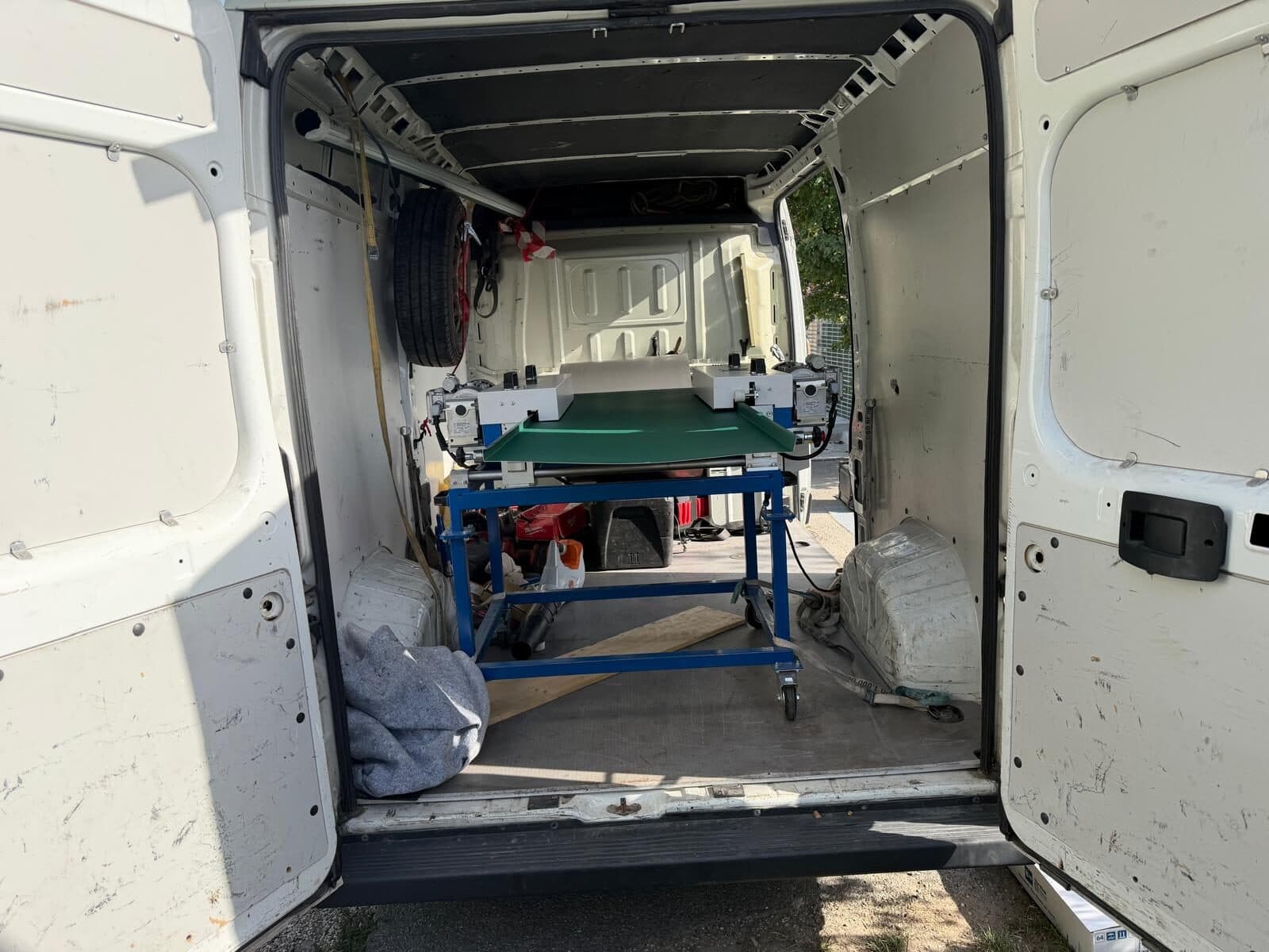 Blick in den offenen Laderaum eines Transporters mit der mobilen Profilieranlage auf einem blauen Rollgestell.